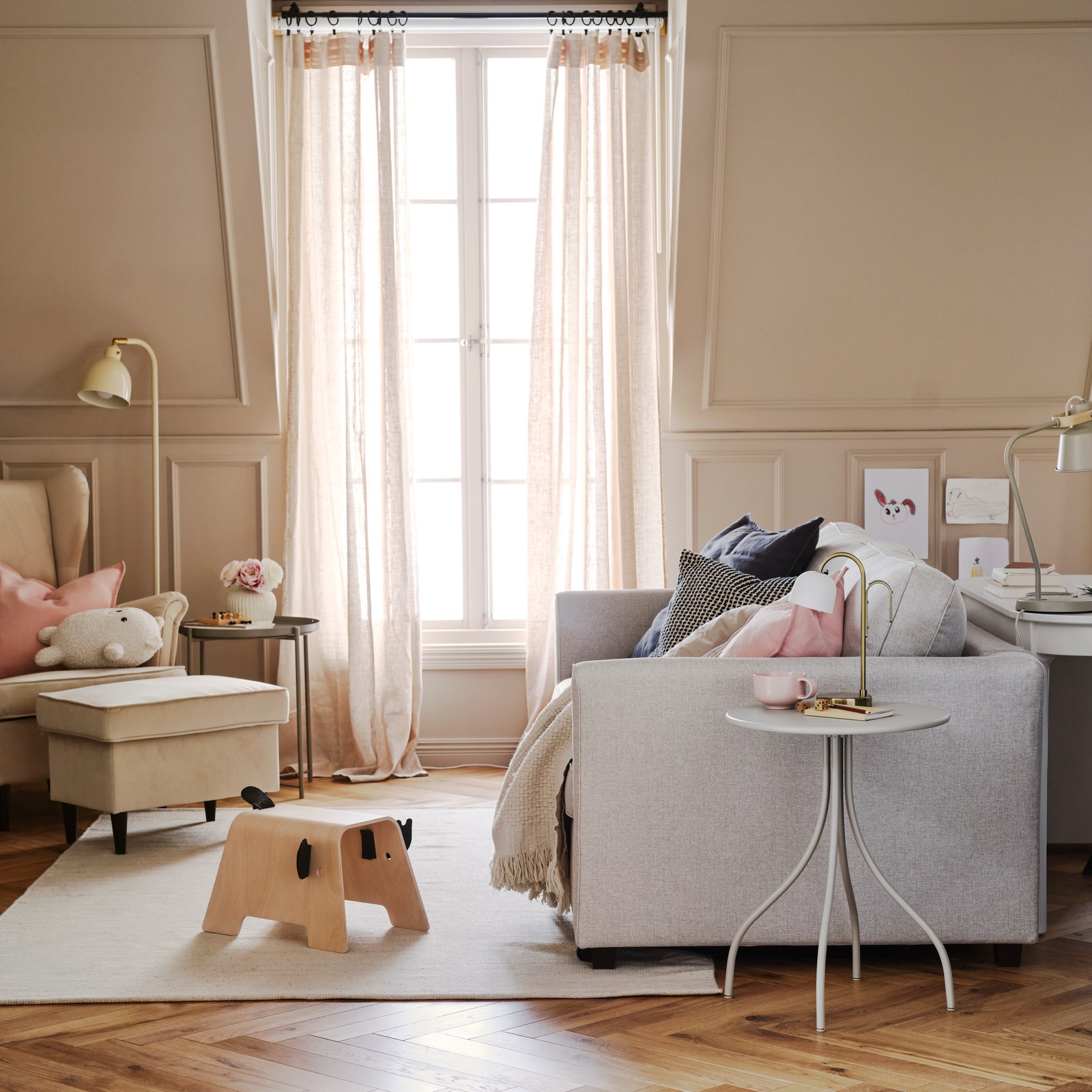 An EKHOLMA 2-seat sofa-bed stands in a multipurpose living room opposite a STRANDMON wing chair with footstool.