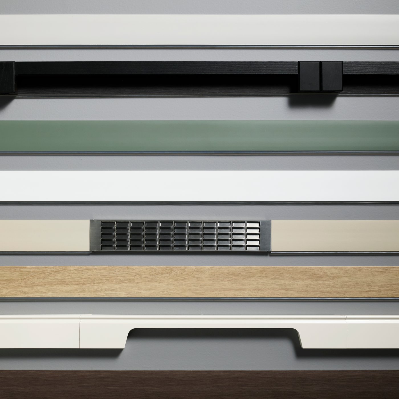 A NICKEBO plinth in matt grey-green placed among other plinths in different colours, finishes, and materials.