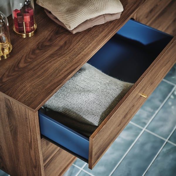 Close-up of RÅDMANSÖ chest of drawers with one drawer pulled out, showing the blue colour inside and the little brass knob.