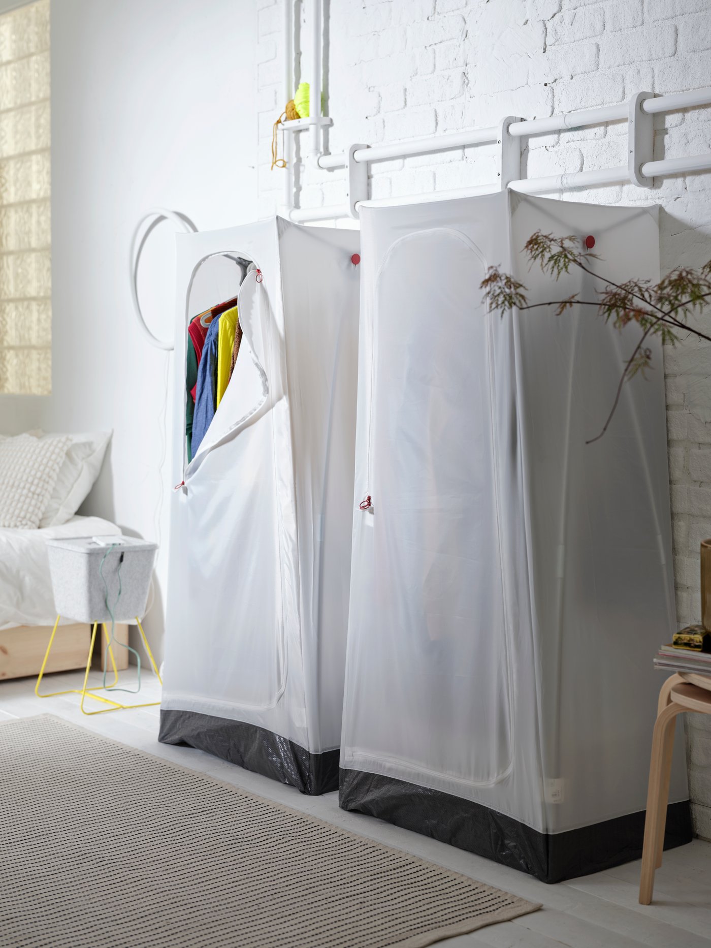 Two white VUKU wardrobes are placed side by side against a wall. There is a STARREKLINTE rug on the floor in front of them.