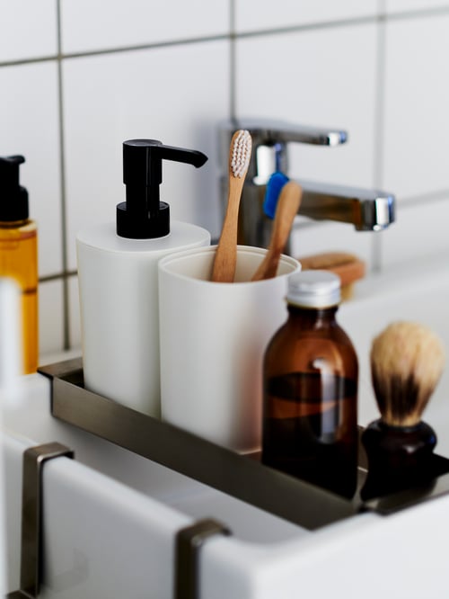 Bathroom close-up of a black and white 3 piece bathroom set consisting of a soap dispenser, a tray and a toothbrush holder.