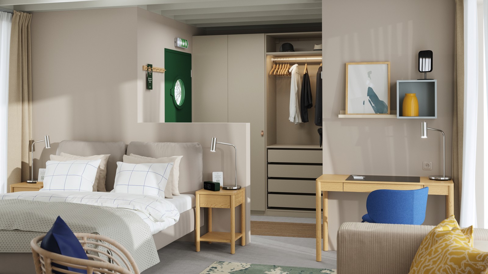 A hotel room with a green front door, a SAGESUND upholstered bed, a bedside table, a PAX wardrobe and a slim desk.