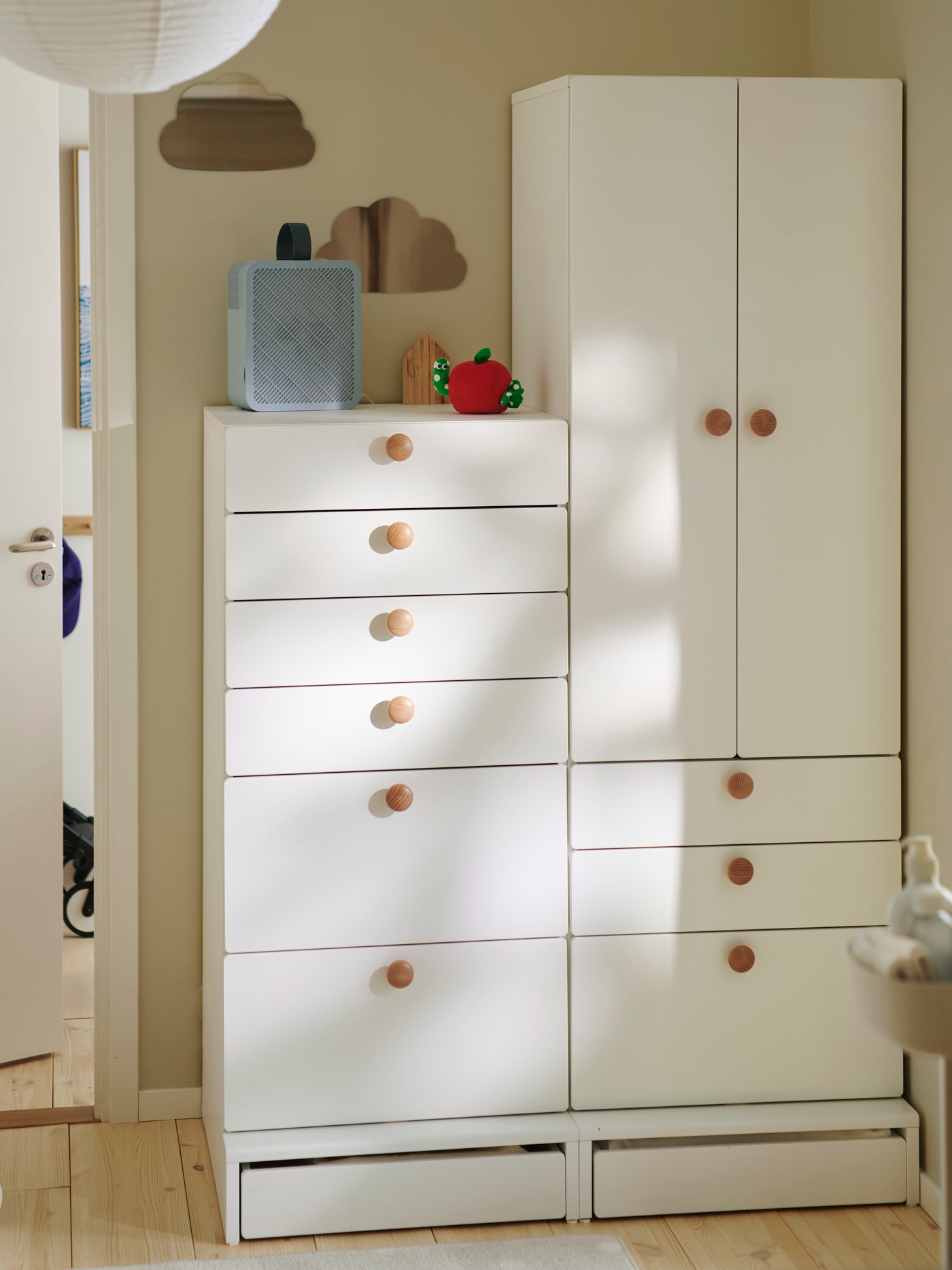 A neutral children’s room with a white SMÅSTAD/UPPFÖRA chest with 6 drawers and matching wardrobe, with round wooden knobs.