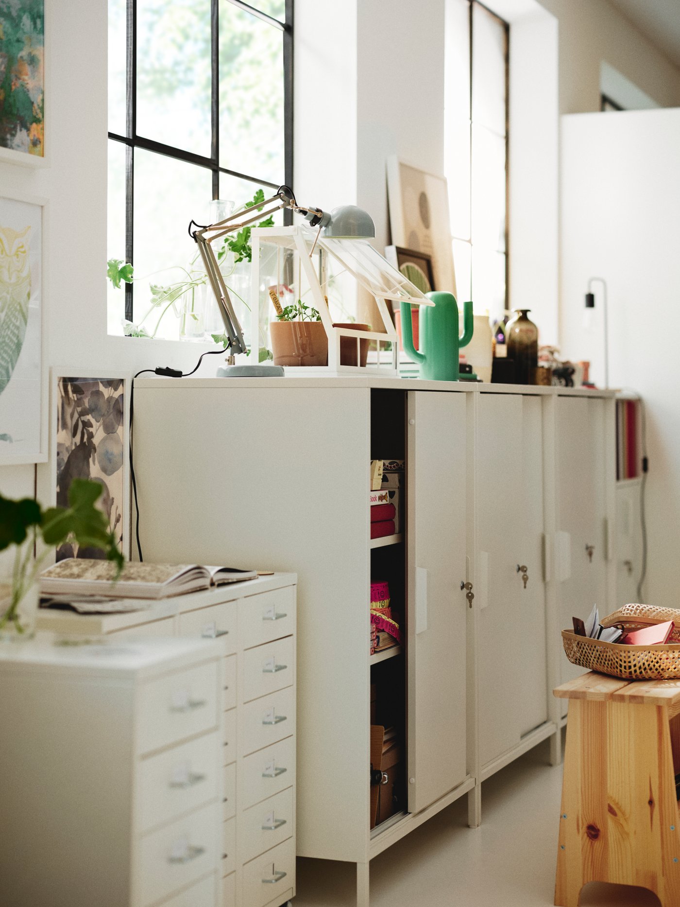 Espacio de trabajo con varios armarios TROTTEN blancos con puertas correderas colocados junto a varias cajoneras HELMER con ruedas.