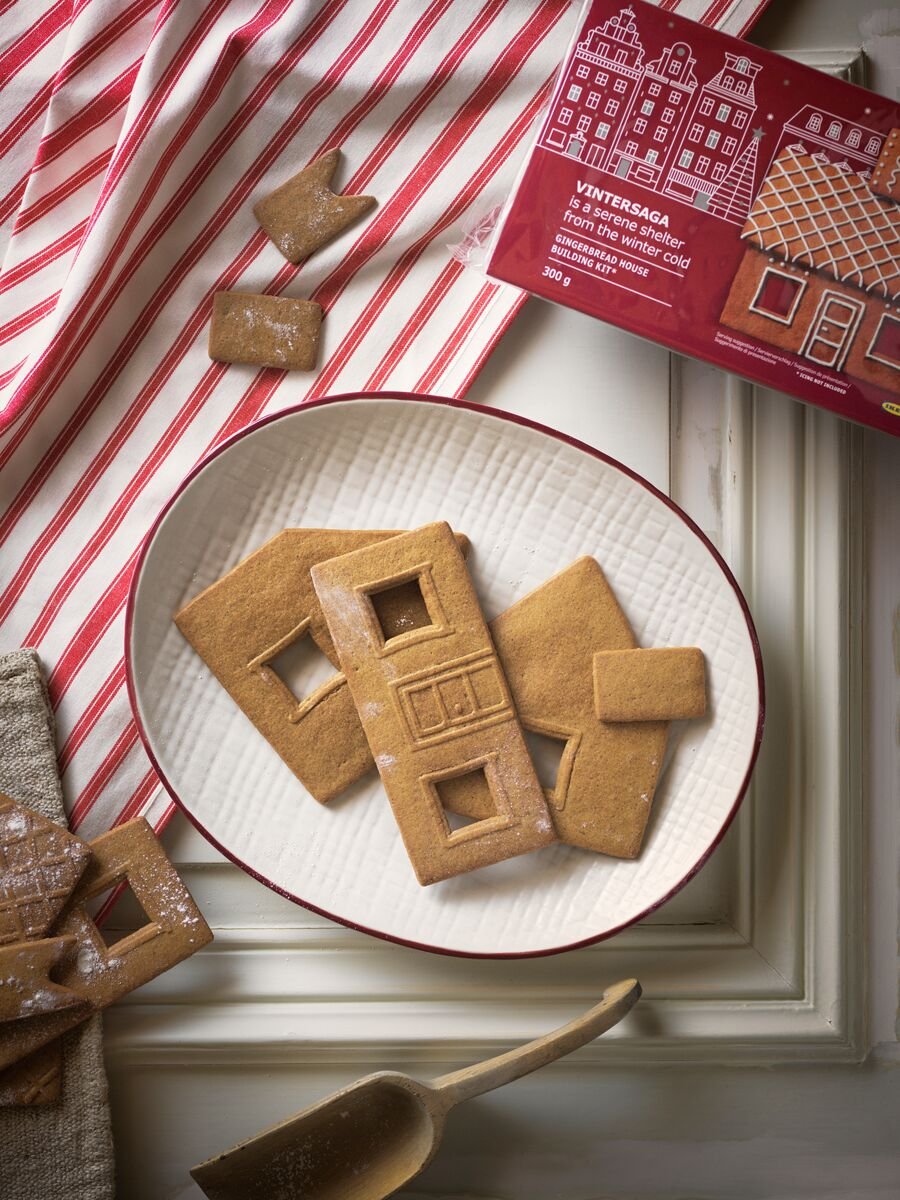 Na bílém talíři s červeným okrajem z kolekce VINTER 2020 leží několik kousků perníkové chaloupky VINTERSAGA.