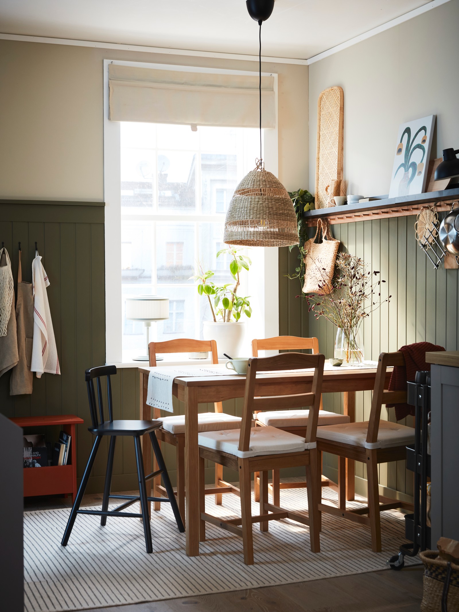 An antique stained pine HÄGERNÄS table and 4 chairs and a black AGAM junior chair stand under a TORARED pendant lampshade.
