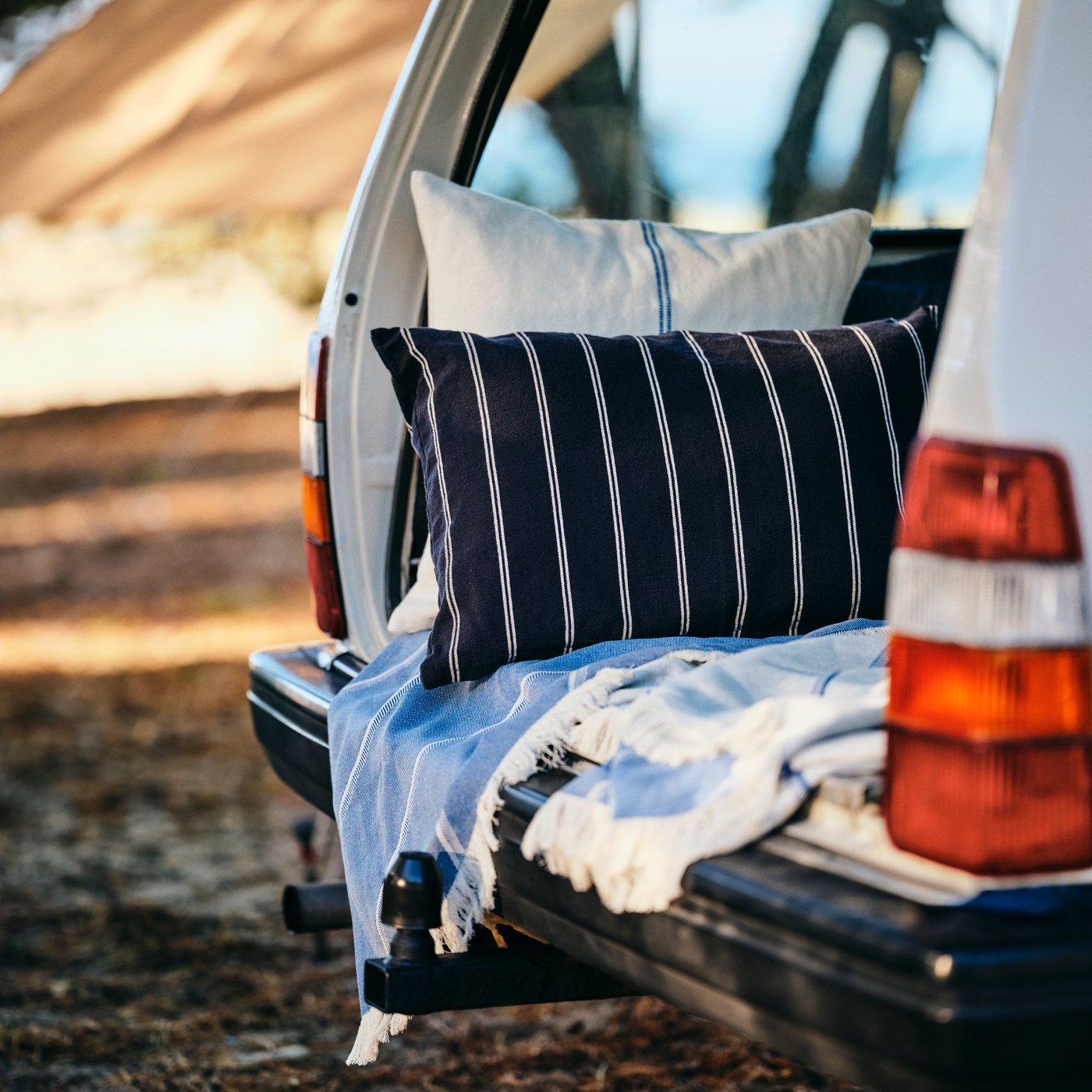 To puder med SOLUPPGÅNG pudebetræk og et SOLUPPGÅNG tæppe skaber en hyggelig krog bag i en bil.