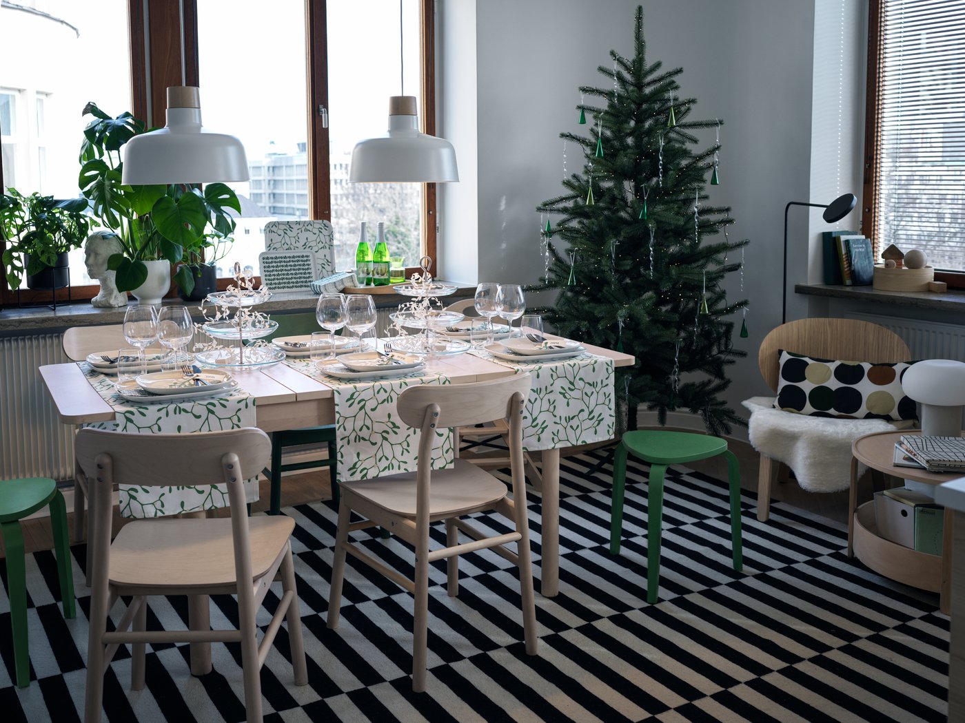 Un comedor de madera sobre una alfombra grande de IKEA. La mesa de comedor está decorada con motivos navideños.