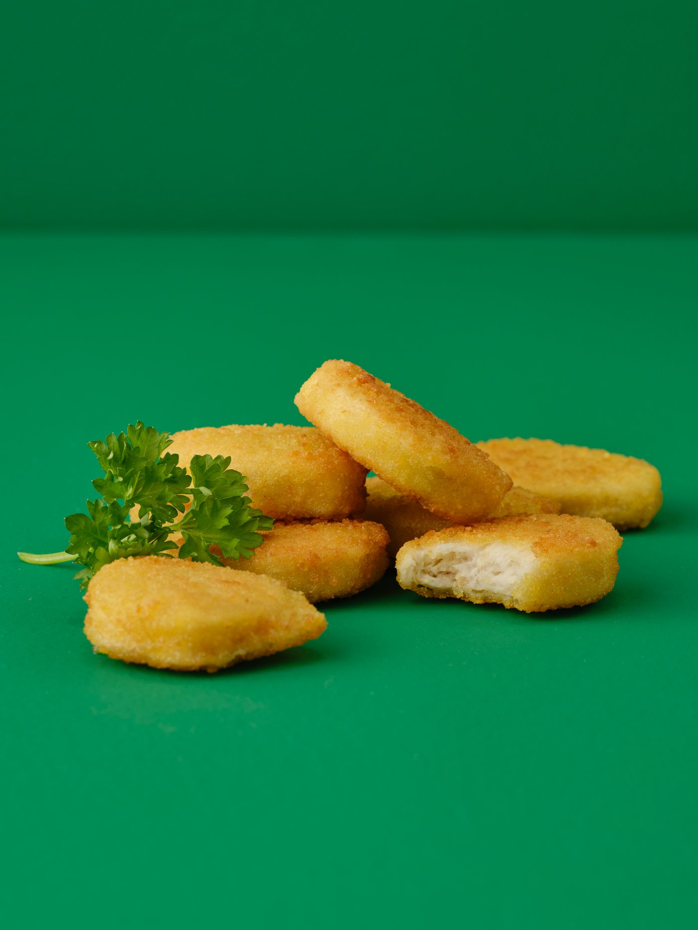 An image with a green background where there are vegetarian nuggets on a dining table.