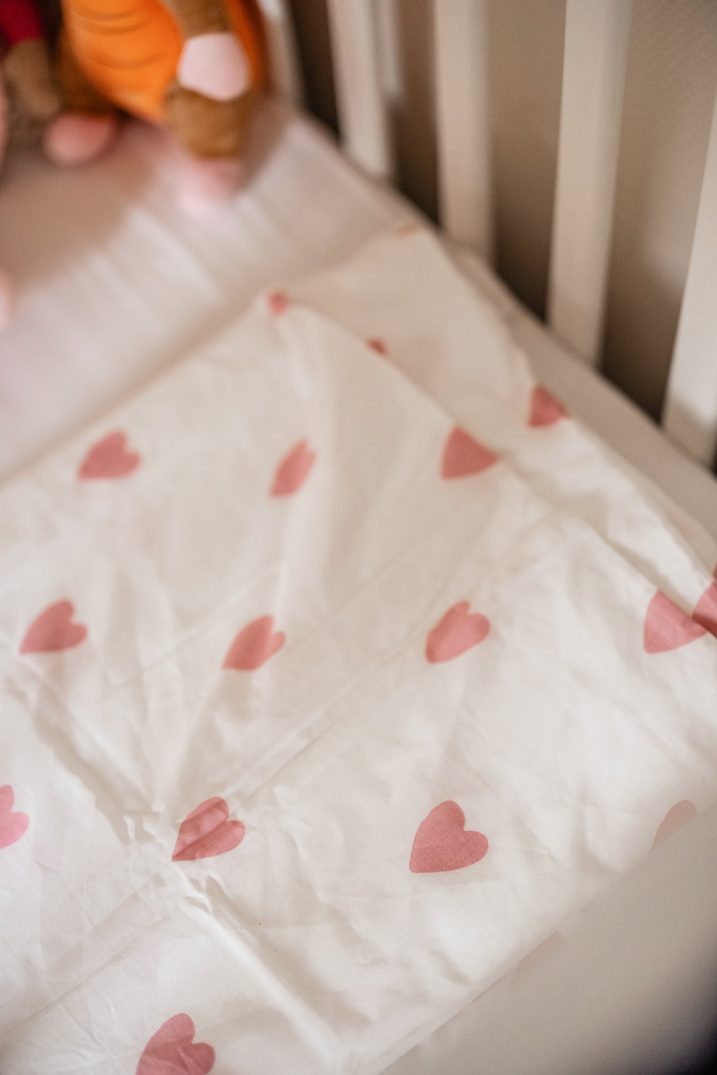 Een wit SUNDVIK babybed met daarin een wit BARNDRÖM dekbedovertrek met hartjespatroon.