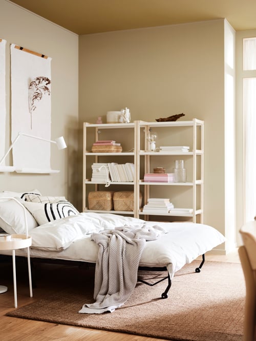 Schlafbereich mit einem LYCKSELE LÖVÅS 2er-Bettsofa, zwei EKENABBEN Regalen, einem BURVIK Beistelltisch und einer NYMÅNE Stand-/Leseleuchte.