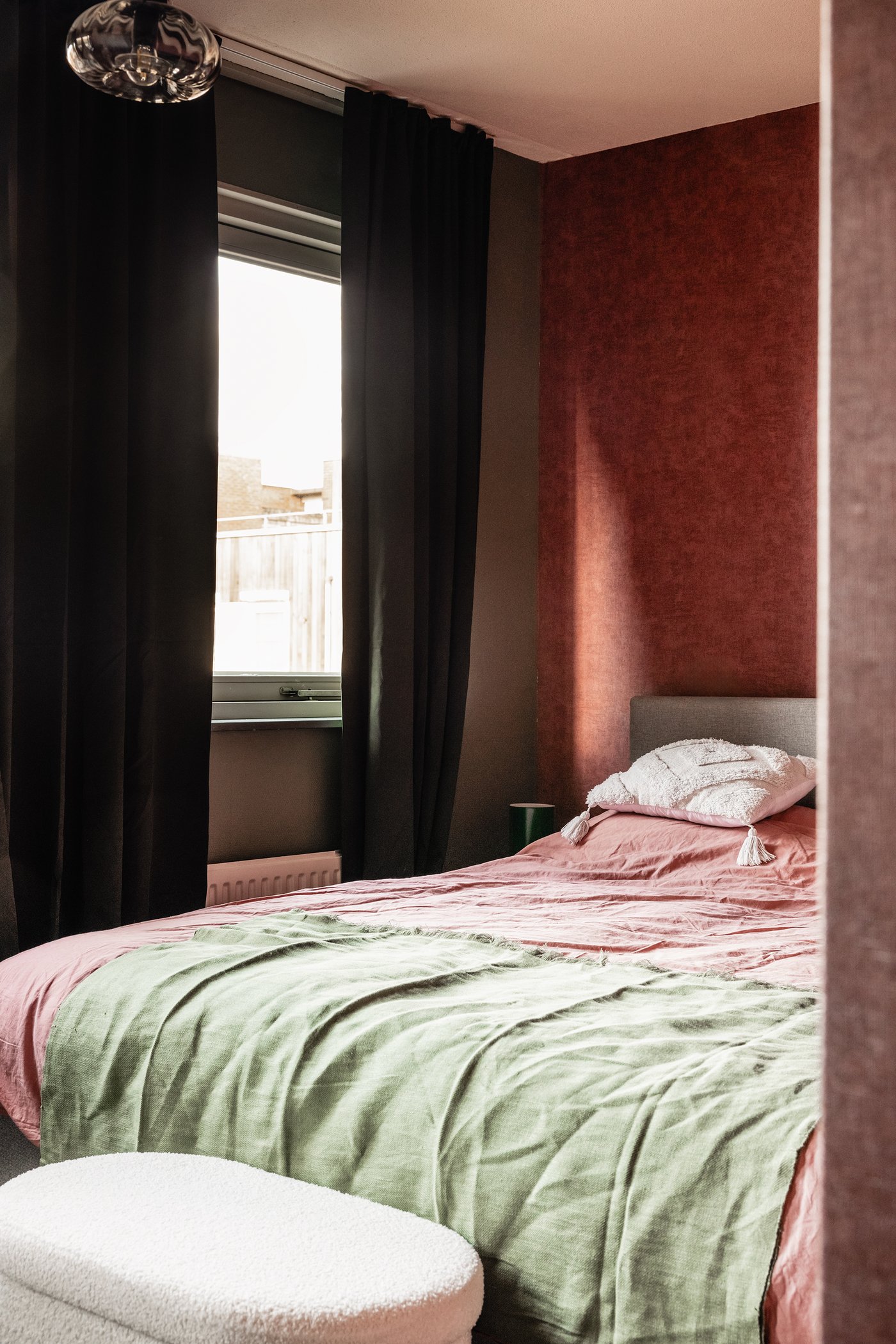 Een slaapkamer met donkerroze ÄNGSLILJA dekbedovertrek en grijsgroen DYTÅG plaid.