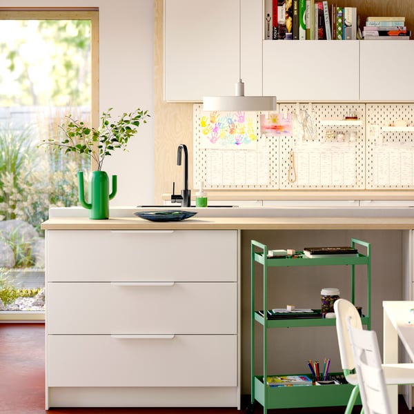 Kitchen storage with VEDDINGE white doors and drawer fronts in white, SKÅDIS pegboards on the wall, and a pendant lamp.