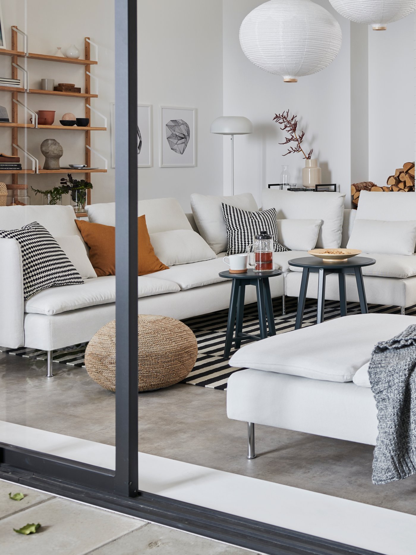 A white SÖDERHAMN six-seater sofa in a bright living room with a beige SANDARED pouffe on a black-and-white STOCKHOLM rug.