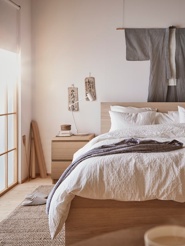 Bedroom with white stained oak MALM bedframe and chest of drawers next to it. 