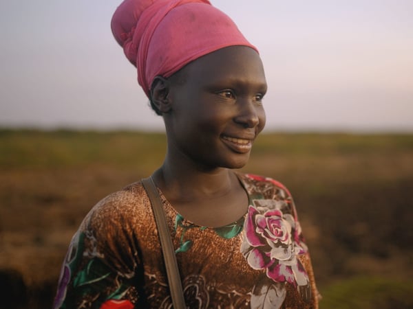 Potriat of a women standing on a open field smiling.