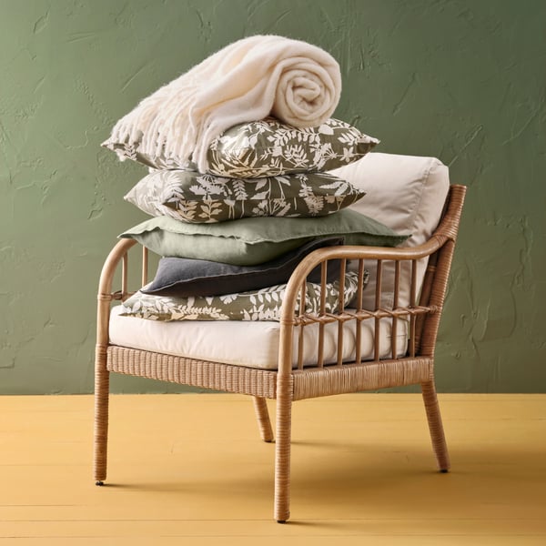 A grey-green/white ROTVECKLARE cushion cover in the NA