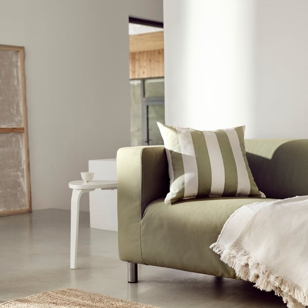 Sofa KLIPPAN w zielonym pokryciu stojąca w jasnym pokoju dziennym.