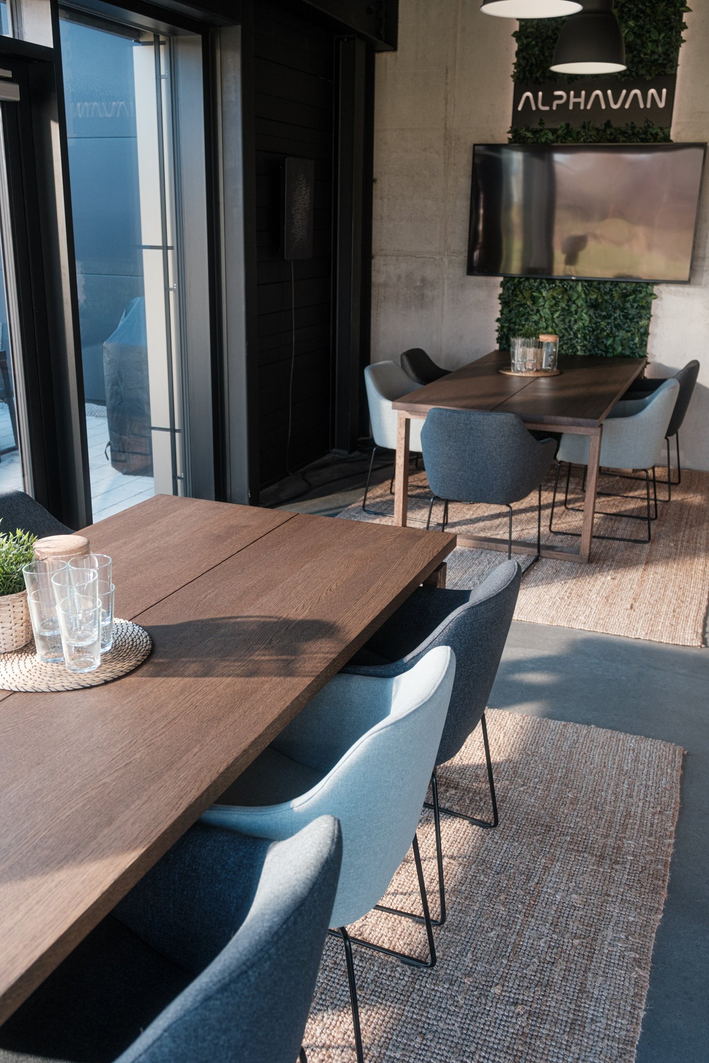 Konferenztisch mit Stühlen und Barbereich mit Hockern und Pflanzen