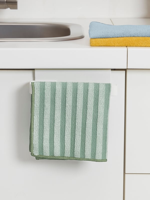 A PEPPRIG Microfiber cloth green with stripes is hanging in front of a kitchen cabinet door. 