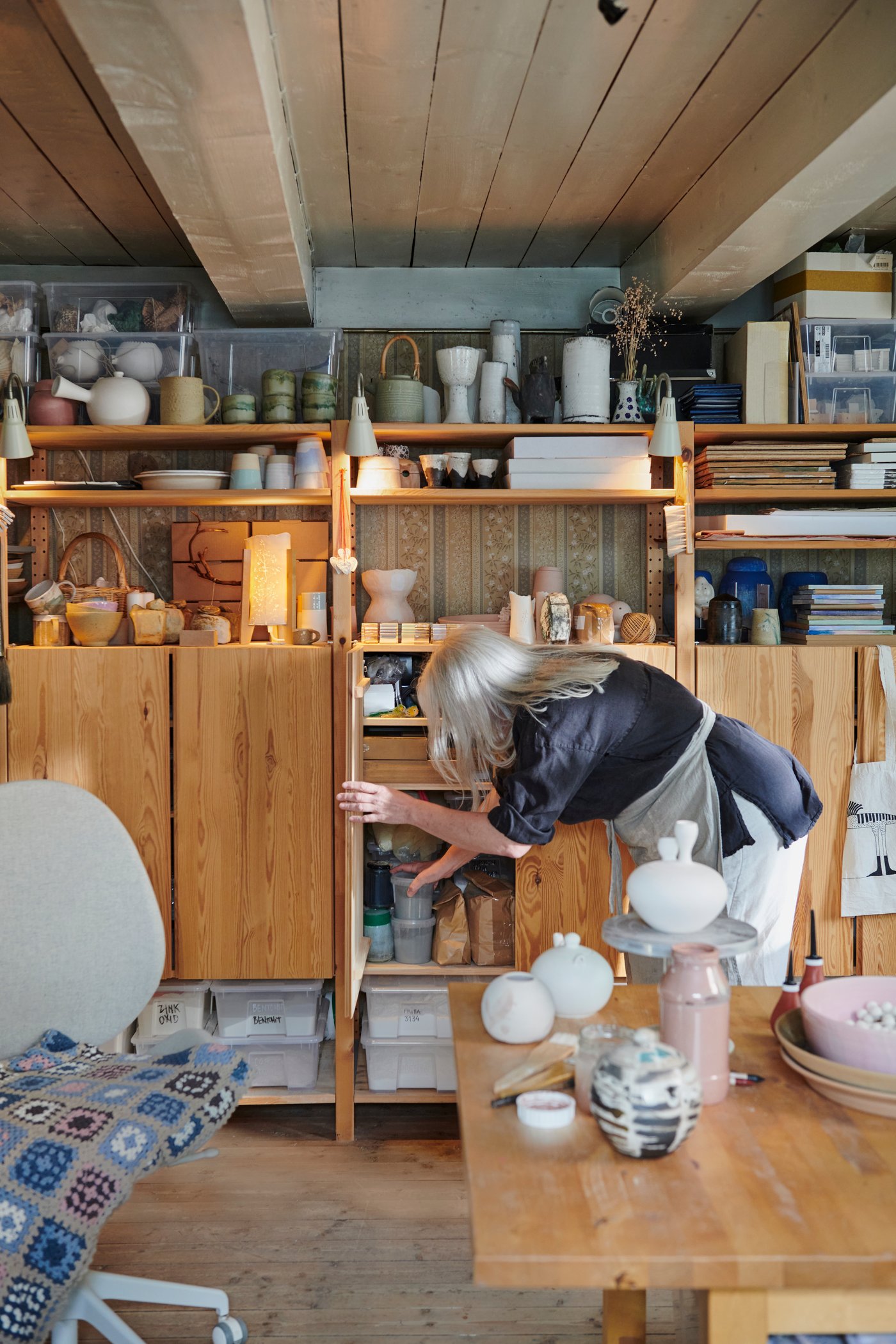 IVAR cabinets and shelving in a multipurpose hobby room, with ceramics and craft items arranged on a table.