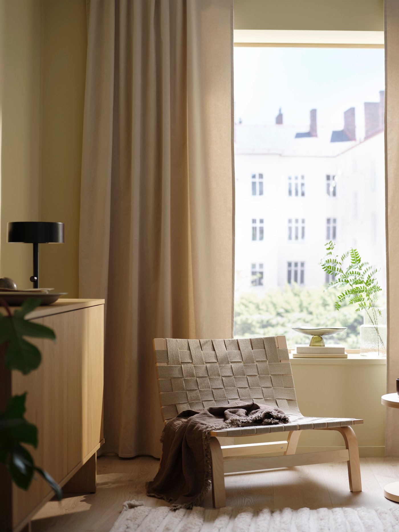 Beige SANELA inbetween gordijnen voor het raam met een beige STOCKHOLM 2025 fauteuil.