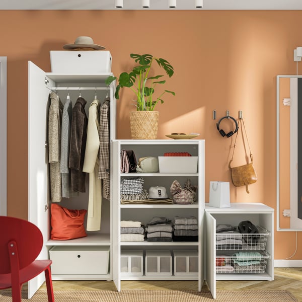 Un armadio a 4 ante PLATSA bianco/bianco Fonnes con ante aperte che svelano degli abiti appesi, contenitori, pile di abiti e cassetti. 