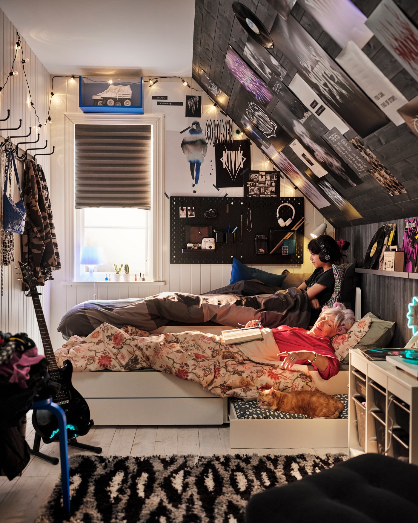 In einem Jugendzimmer hängt ein schwarzes SCHOTTIS Verdunkelungsrollo. Passend dazu wurde eine Wandschräge schwarz gestrichen und mit verschiedenen Postern dekoriert.