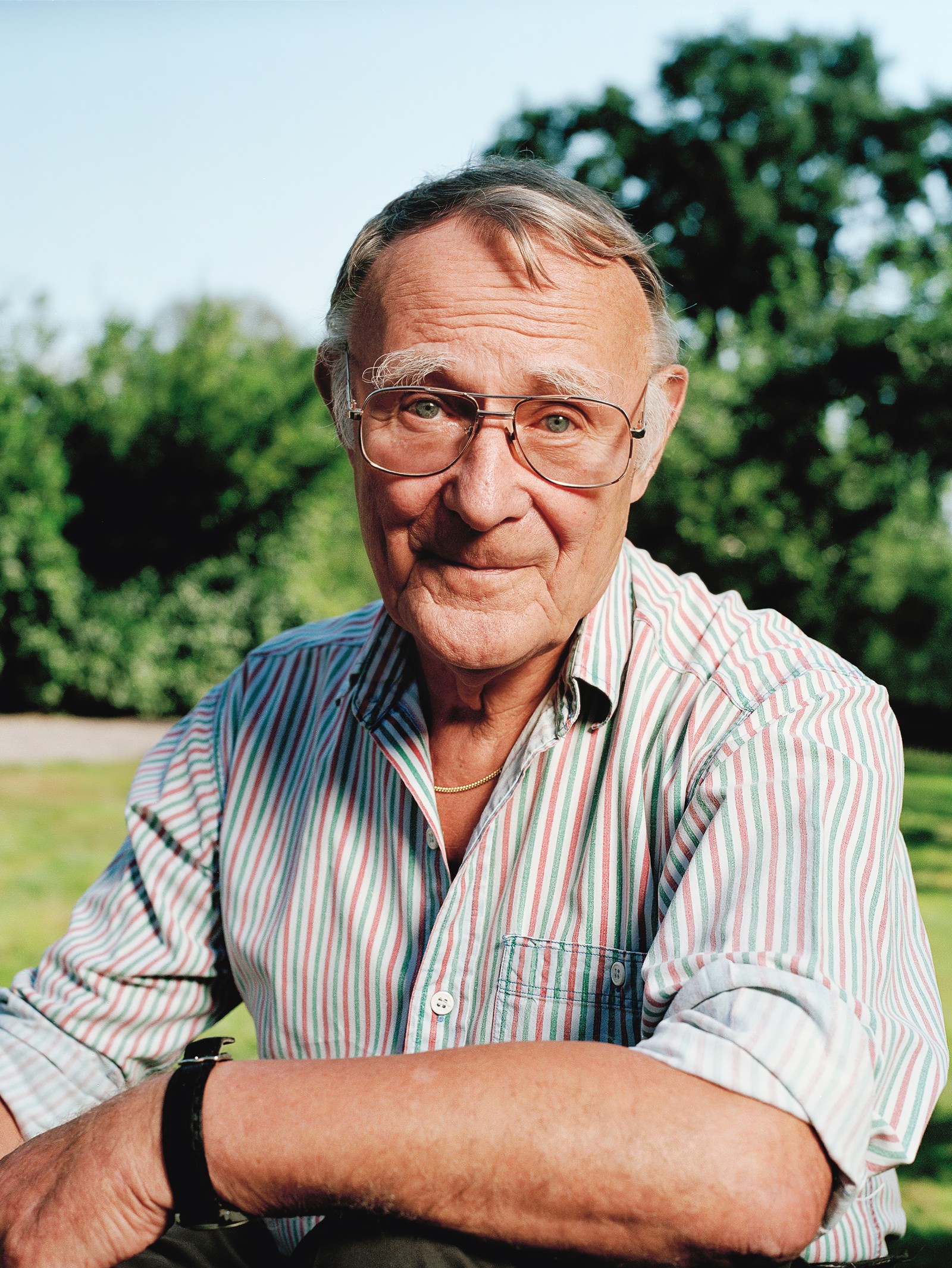 Portret osnivača kompanije IKEA Ingvara Kamprada, nasmejanog napolju, u košulji s roze, belim i zelenim prugama.