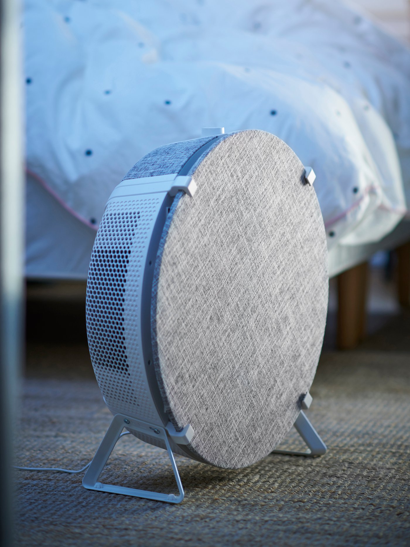 Biały oczyszczacz powietrza STARKVIND stojący w sypialni.