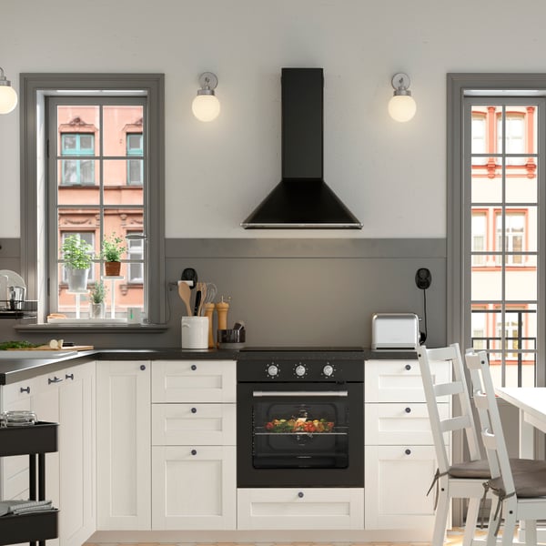 Una cucina bianca e nera in stile tradizionale con frontali bianchi ENKÖPING, un tavolo da pranzo NORDVIKEN bianco circondato da tre sedie e da una panca in pino.