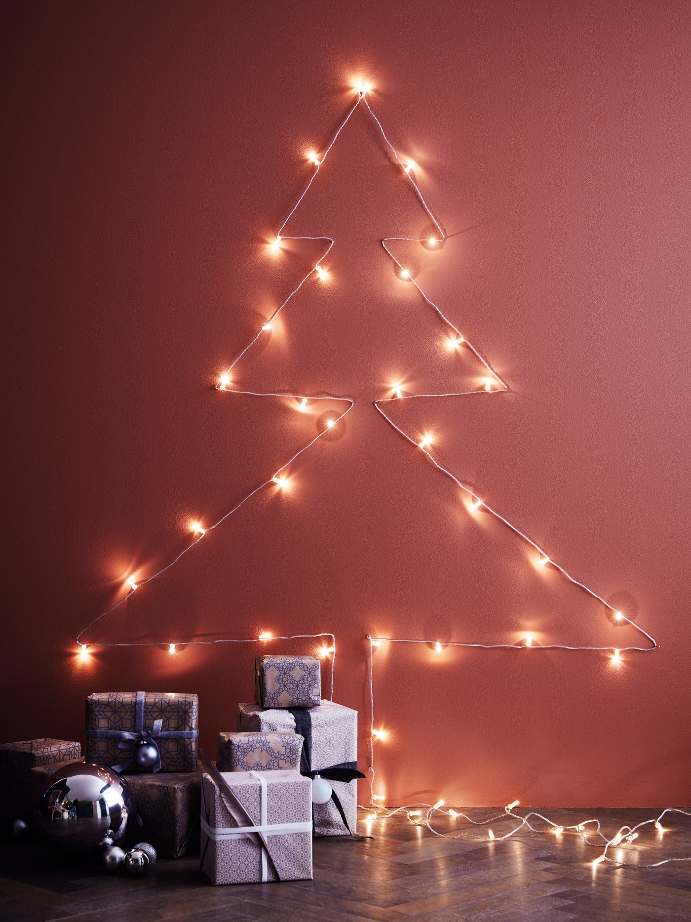 Hange your light chain on the wall in the shape of a Christmas tree.