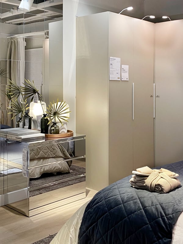 Een MALM ladekast met glimmende buitenkant naast een gesloten, beige PAX kast in een rustige slaapkamer