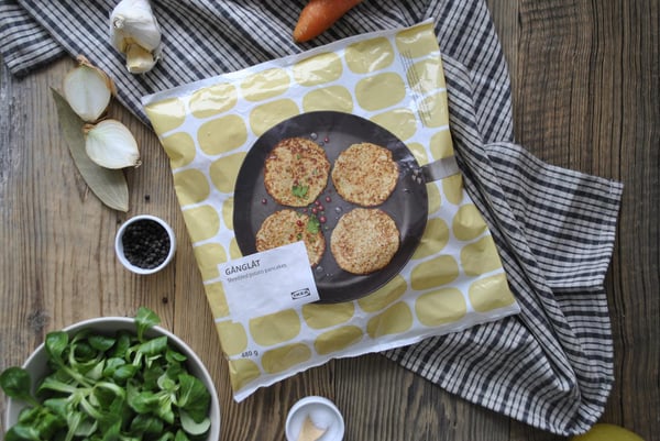Disposition à plat des ingrédients avec un paquet de burgers végétariens GÄNGLÄT, des légumes frais et un bol de salade sur une surface en bois.