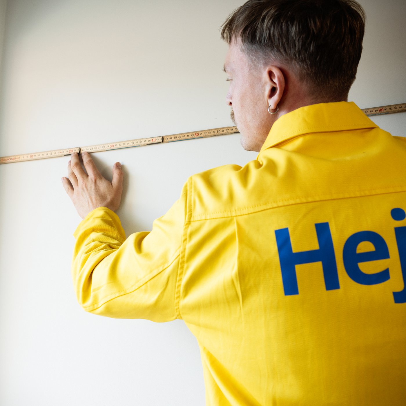 A man measuring a wall with a measuring tape.