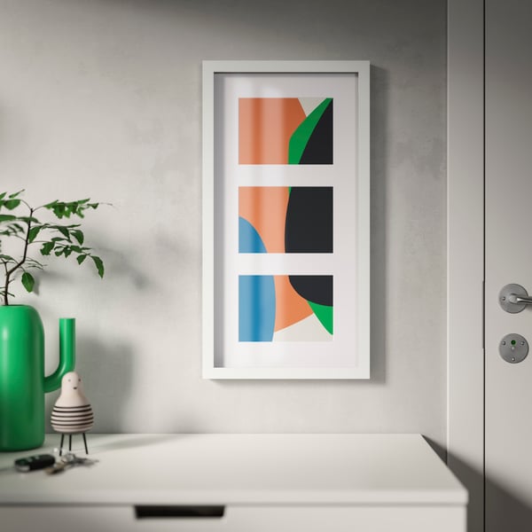 An IKEA RÖDALM white collage picture frame for 3 pictures, mounted on a grey wall on top of a chest of drawers. 