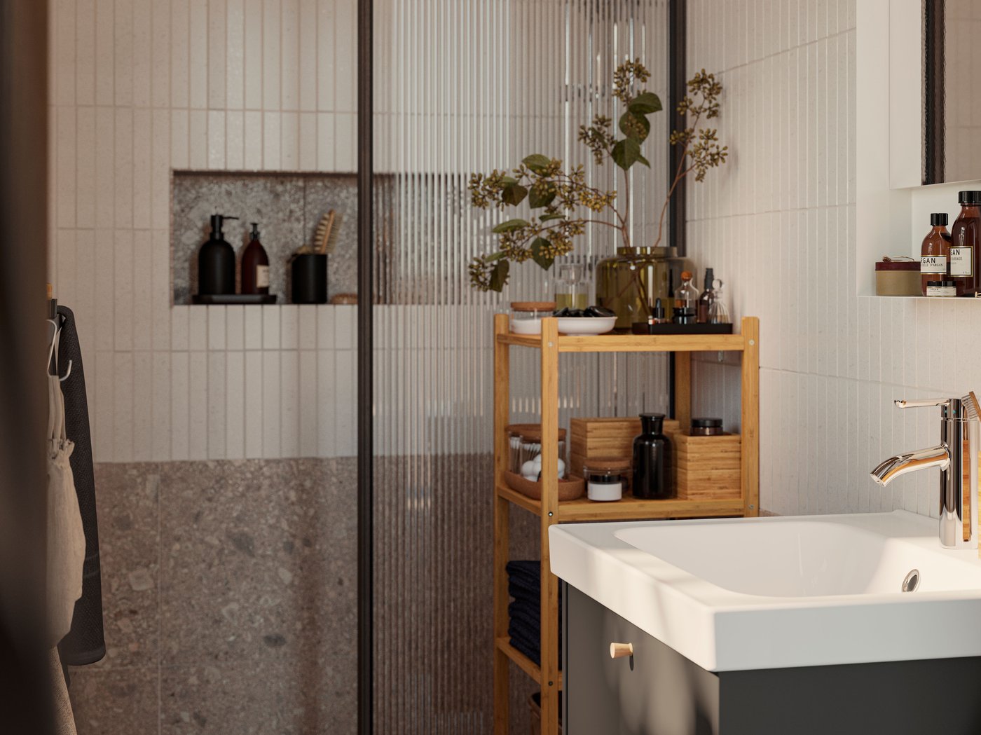 A HAVBÄCK wash-stand in dark grey with a white ORRSJÖN washbasin is standing next to a RÅGRUND shelf made of bamboo.
