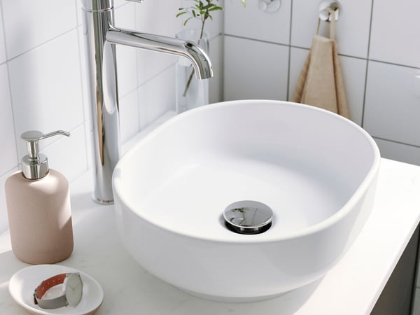 Vasque blanche et robinet dans une salle de bain lumineuse.
