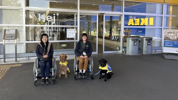 車いすに座った人物二人と介助犬/訓練犬
