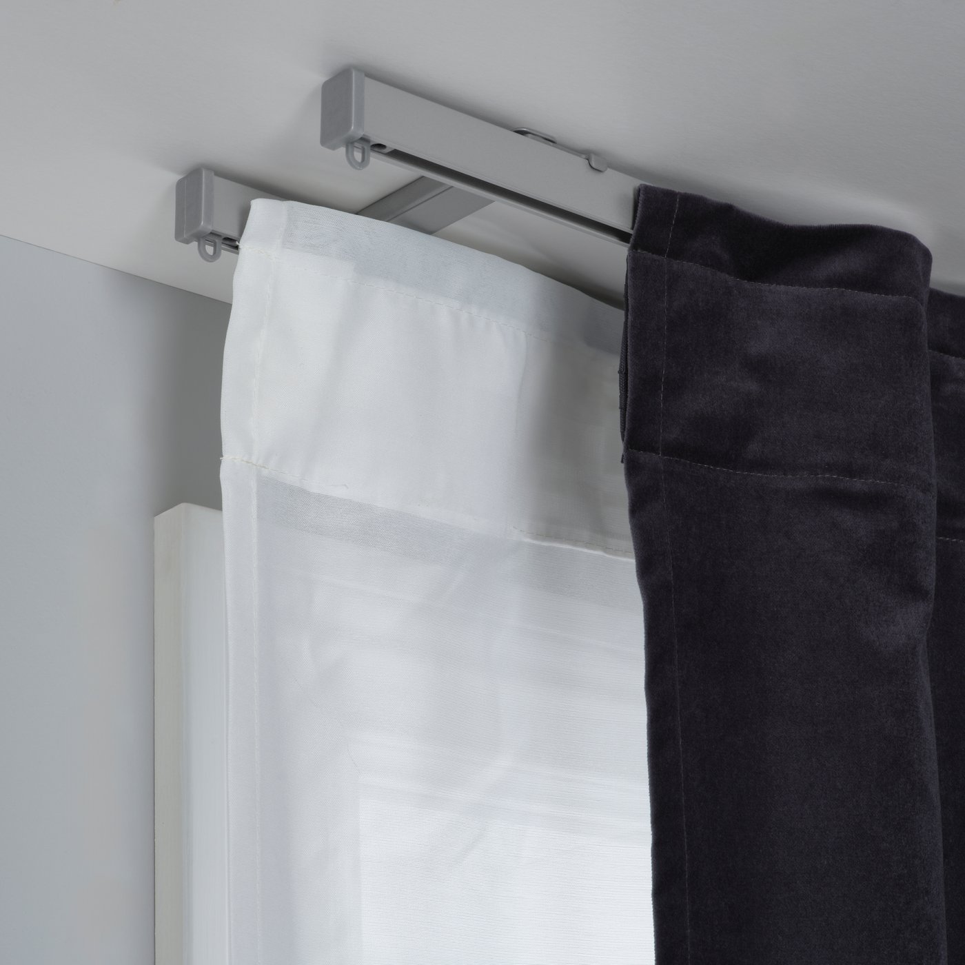 Dettaglio di due binari singoli per tenda VIDGA su cui sono sono agganciate due tende, una bianca e una nera. 