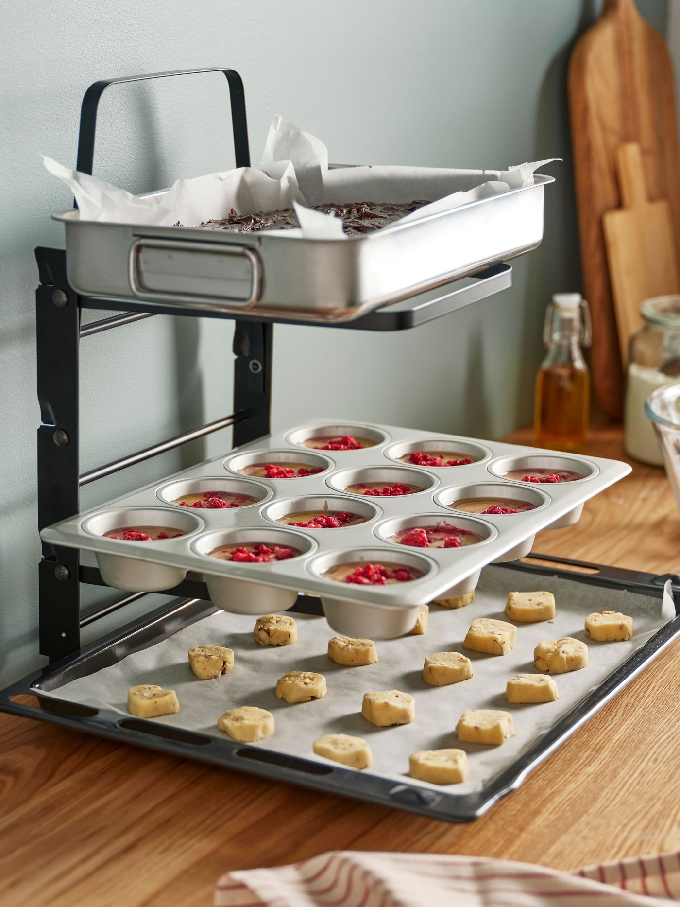 Et static til bageplader hvor på der står en bageplade, en muffinform og en bradepande.