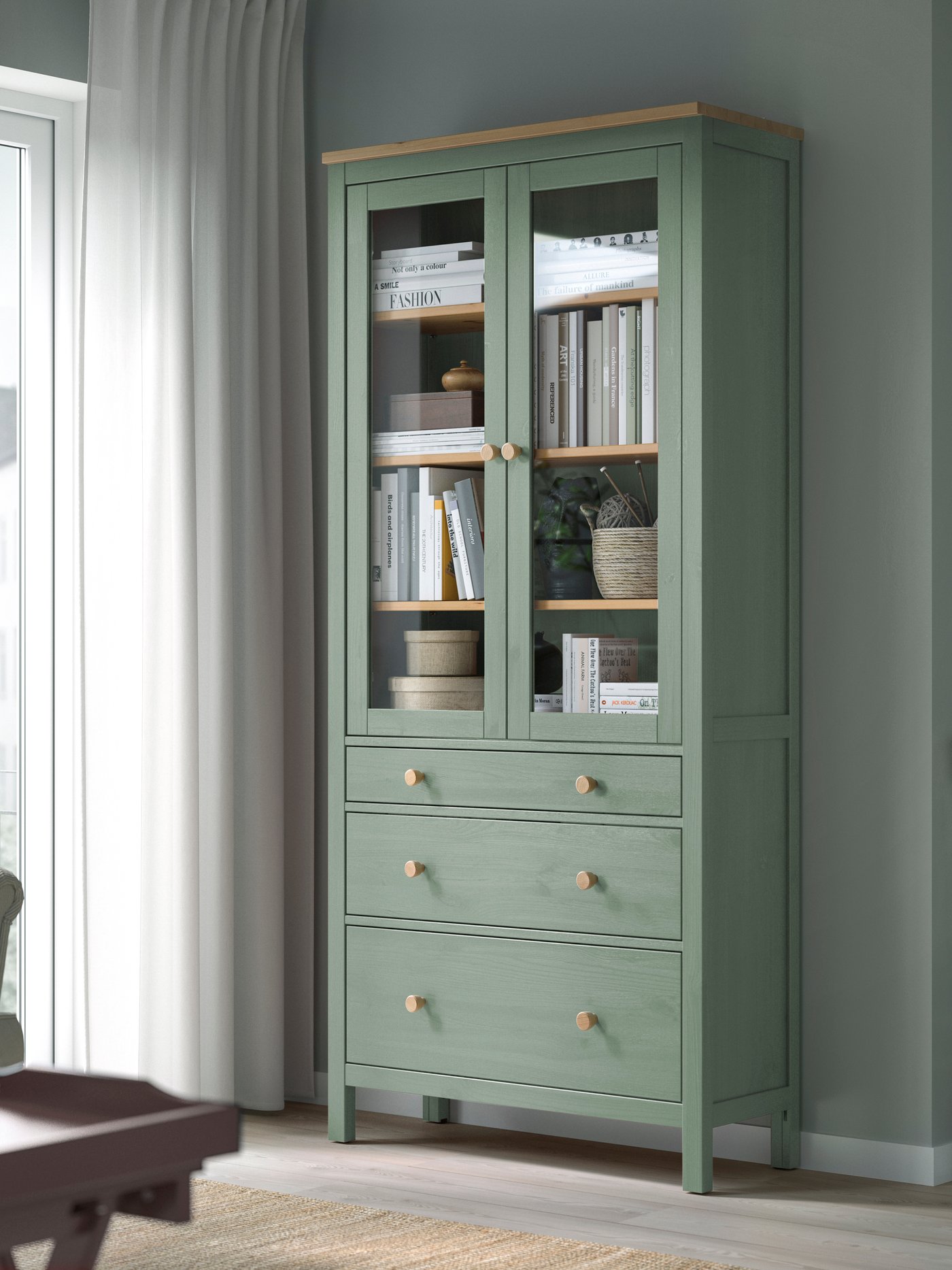 Une armoire HEMNES à portes vitrées, teinte gris-vert/marron clair, avec 3 tiroirs.