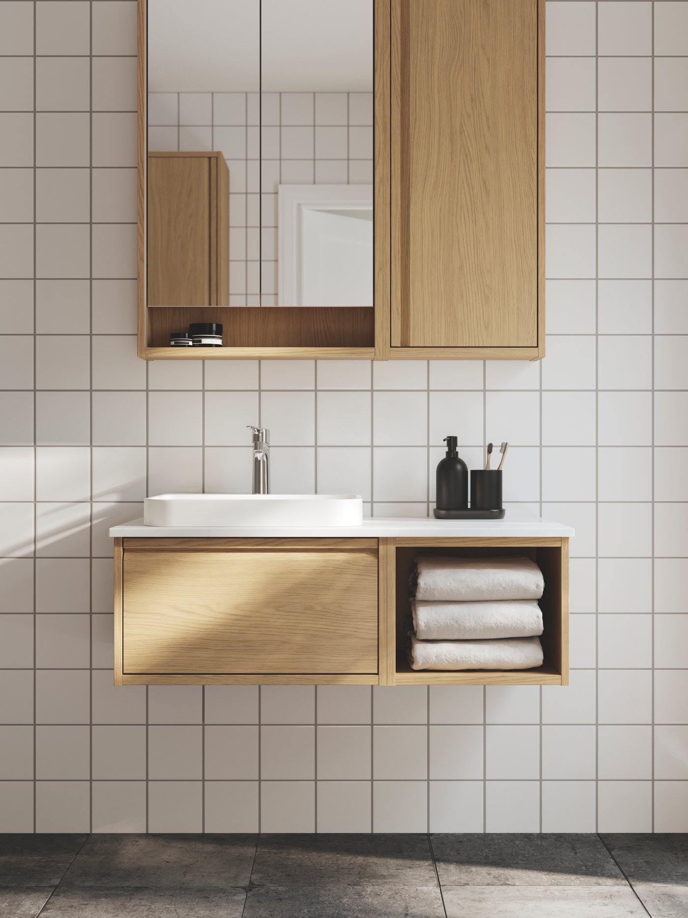 Un baño con paredes blancas, tiene un lavabo ÄNGSJÖN en efecto roble con un lavabo semiempotrado blanco y un armario con espejo.