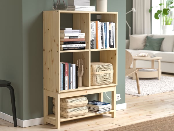 A pine IVAR shelving unit with books and various items on the inside.