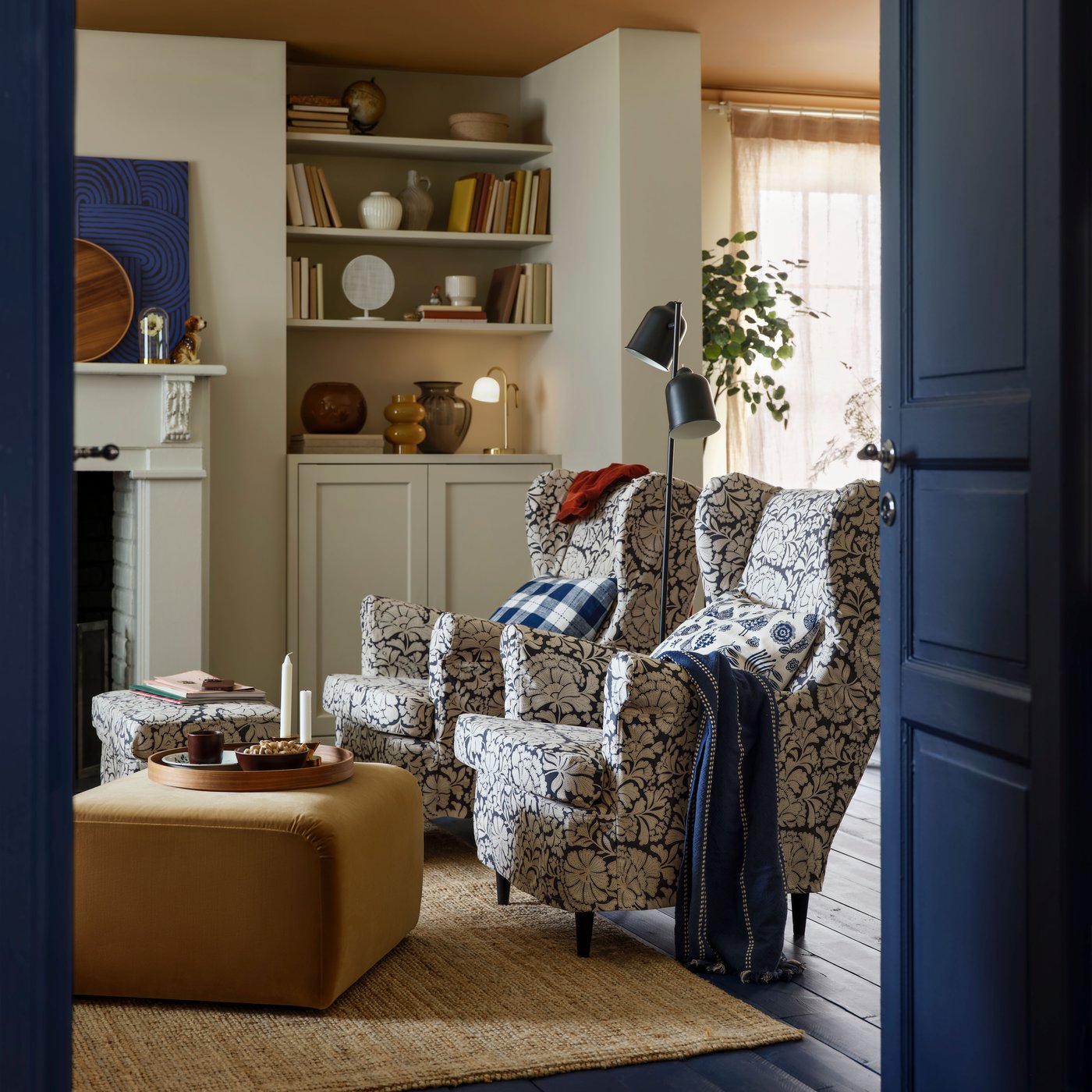 Zwei blau weiß gemusterte Sessel mit Hocker stehen nebeneinander in einem Wohnzimmer.