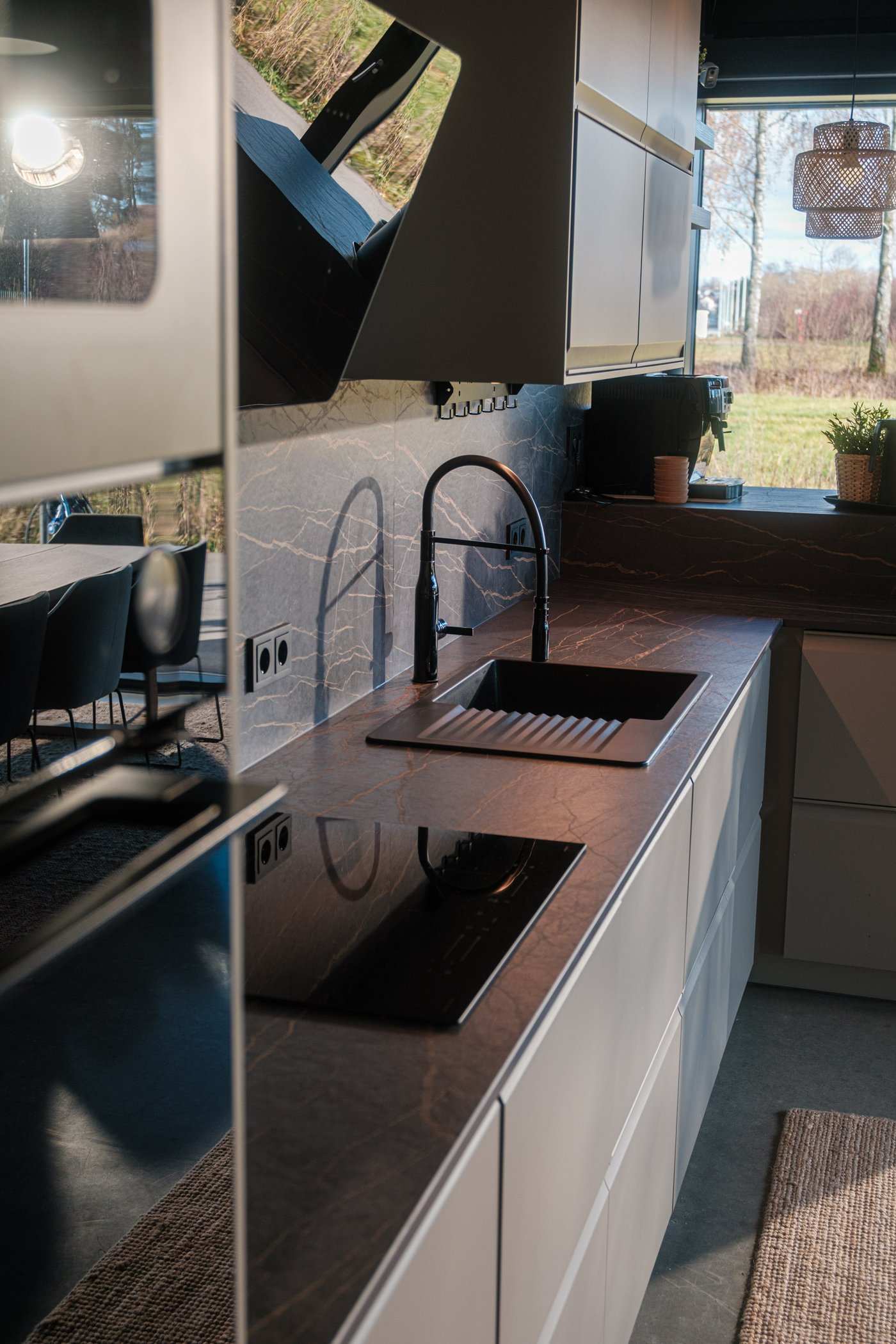 Moderne Küche mit beigen Schränken, schwarzer Dunstabzugshaube