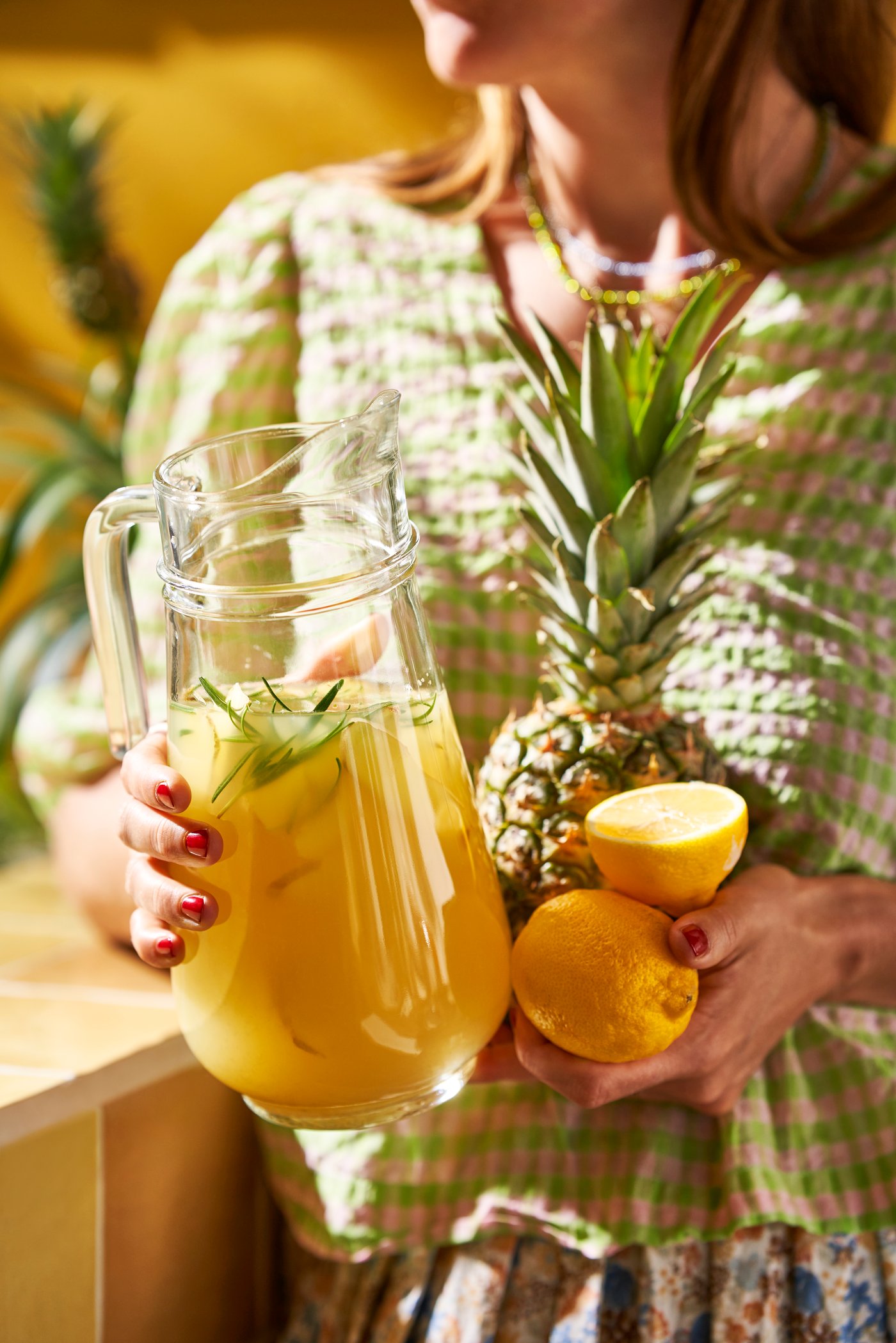 여성이 파인애플과 레몬, 그리고 과일 쥬스를 안고 있다