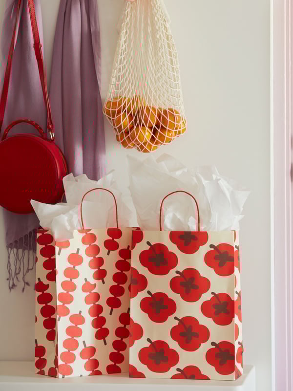 Two FÖSSTA paper gift bags with mixed patterns are placed on a white surface. White wrapping paper sticks out from the bags.