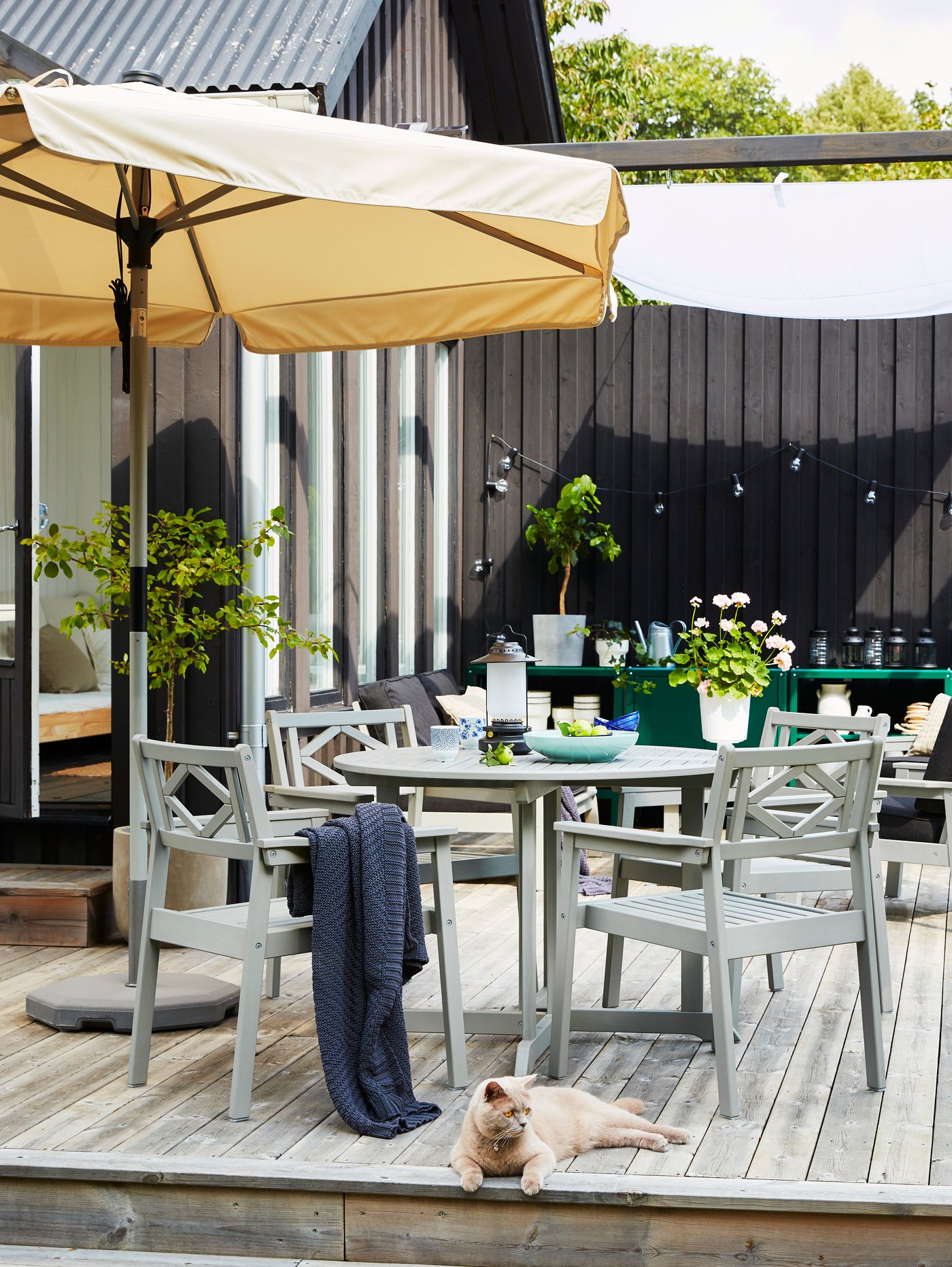 Una mesa de comedor gris para exterior con una sombrilla marrón encima.