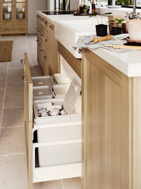Grand tiroir de cuisine avec face VEDHAMN ouvert, révélant cinq poubelles gris clair. Le couvercle de l’une d’entre elles est ouvert.